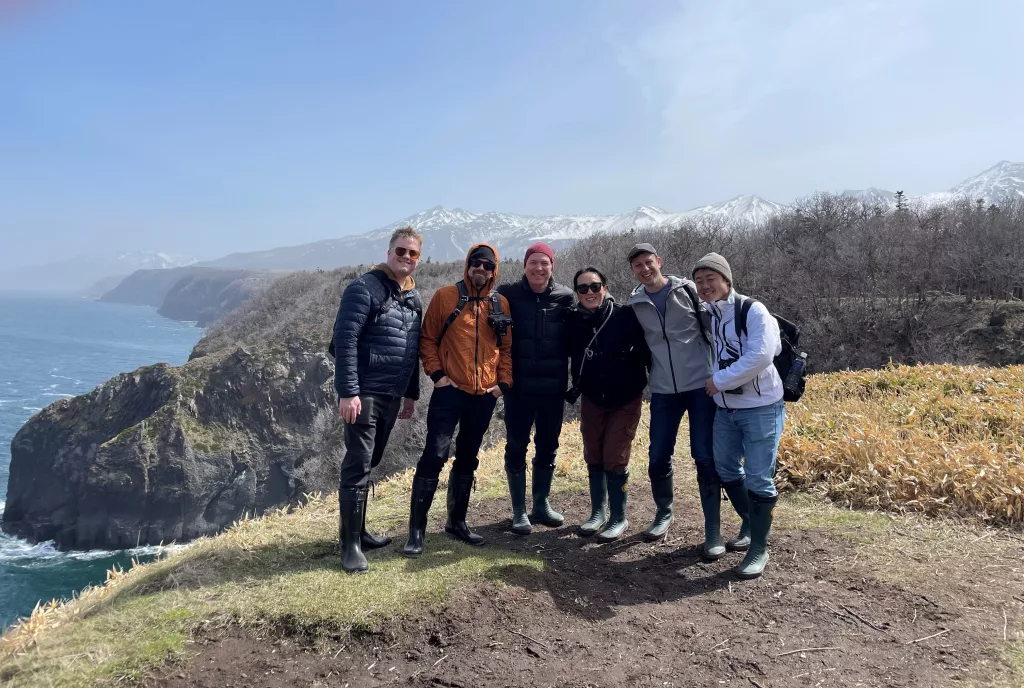 Equipe de pesquisa da Suker Punch tirando fotos juntos em uma paisagem montanhosa.