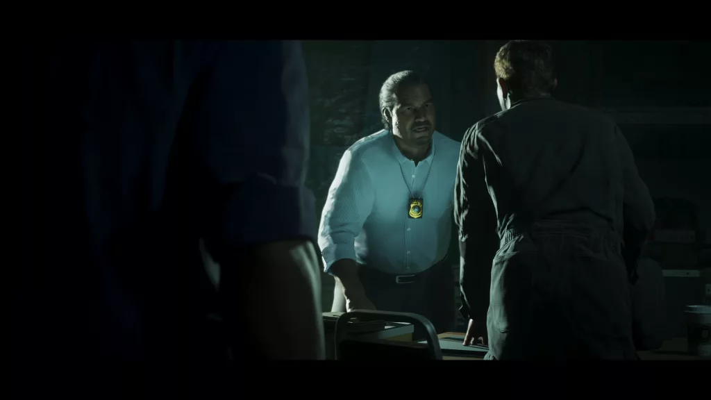 Policial em uma sala escura conversando com algumas pessoas.