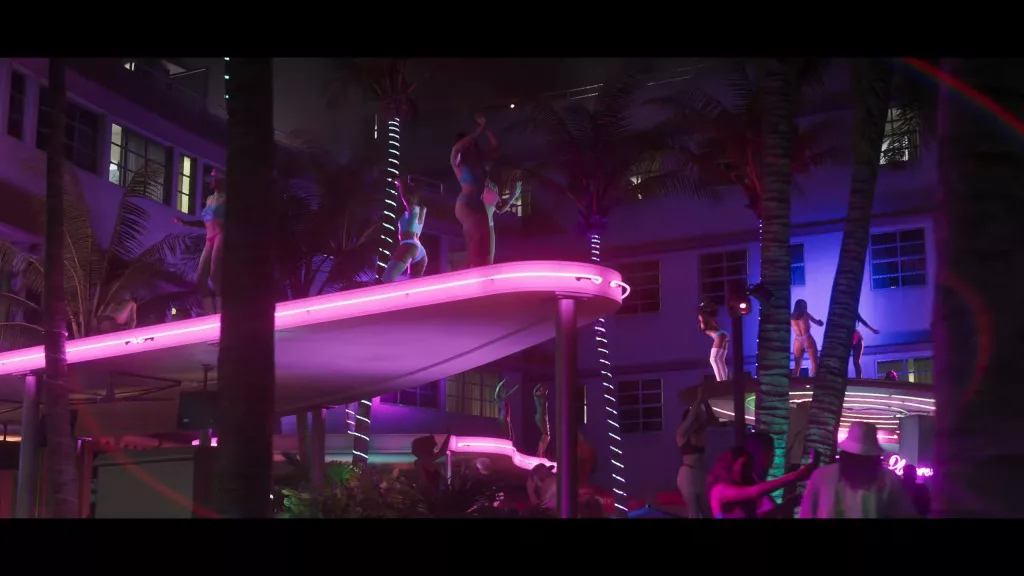 Noite, muito neon rosa e azul, pessoas em trajes de praia, muitas palmeiras no que parece ser uma festa.
