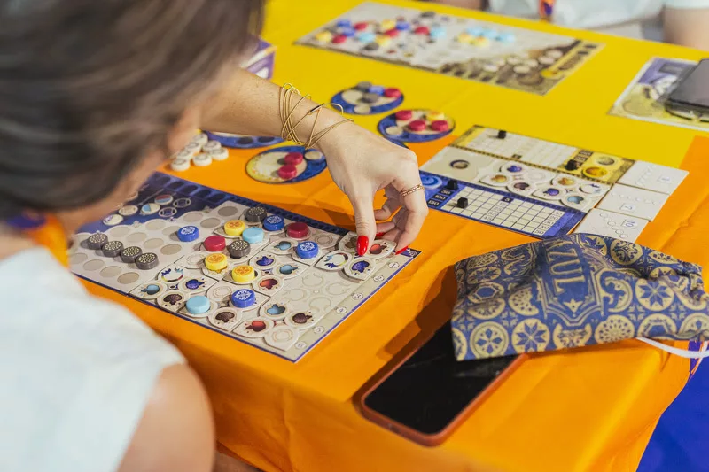 Pessoa jogando o Board Game Azul em uma mesa laranja.