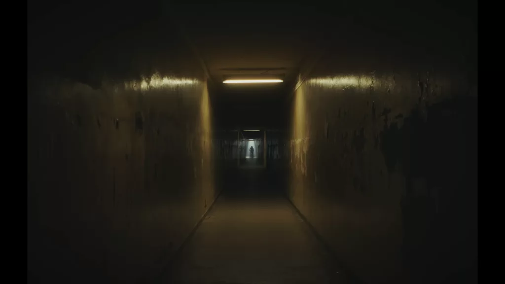 Personagem do curta ao fundo de um corredor com poucas luzes.