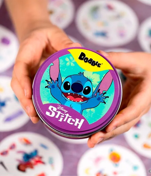 Mãos apresentam uma caixa circular metálica com a versão Dobble Stitch da Galápagos e Disney.