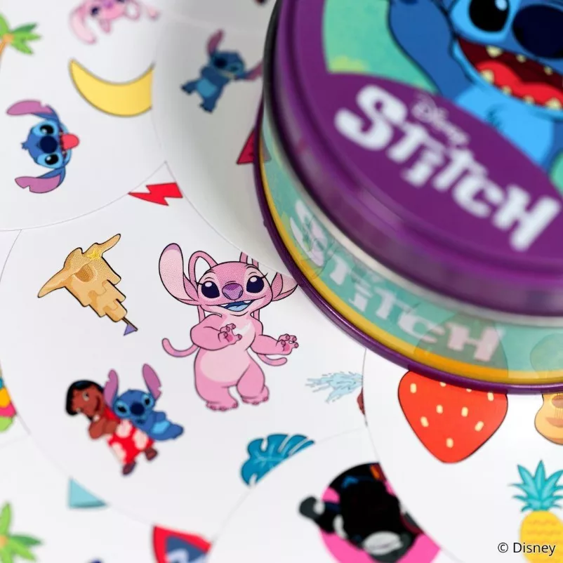 Vários Cards de Dobble Stitch em baixo da caixa metálica do jogo.