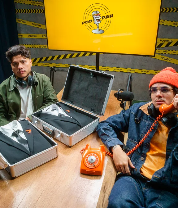 Mítico e Igão do PodPah sentados à mesa com um telefone laranja e dois ternos do The Replacer de Call of Duty Black Ops 7.