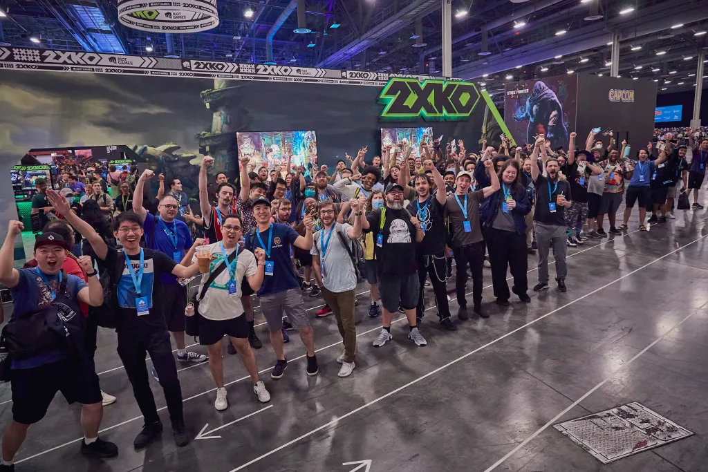 Pessoas em estande do 2XKO durante Evento.