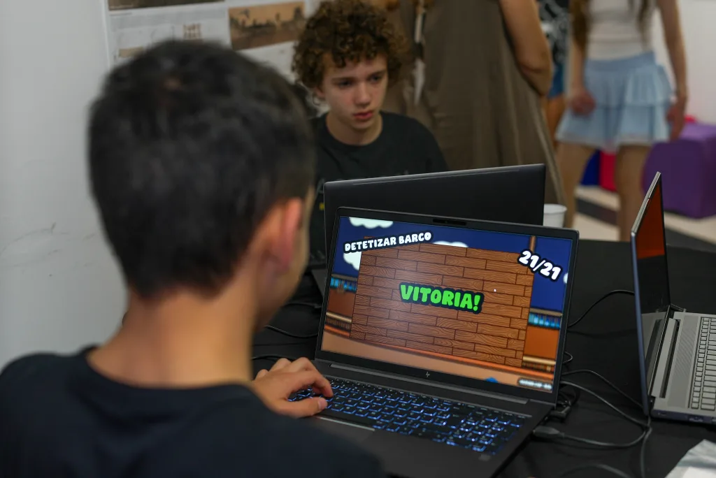 Dois jovens em notebooks jogando "O Barco de Clebinho"