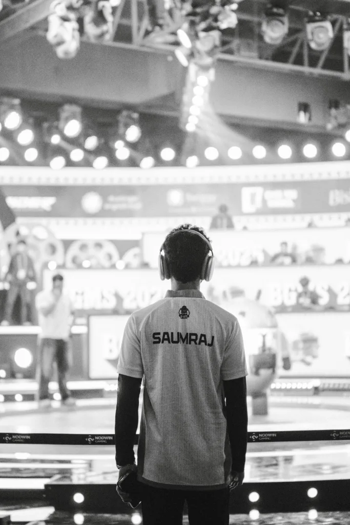 Jogador de liga profissional, de costas e com Headset, em pé e olhando para o cenário.