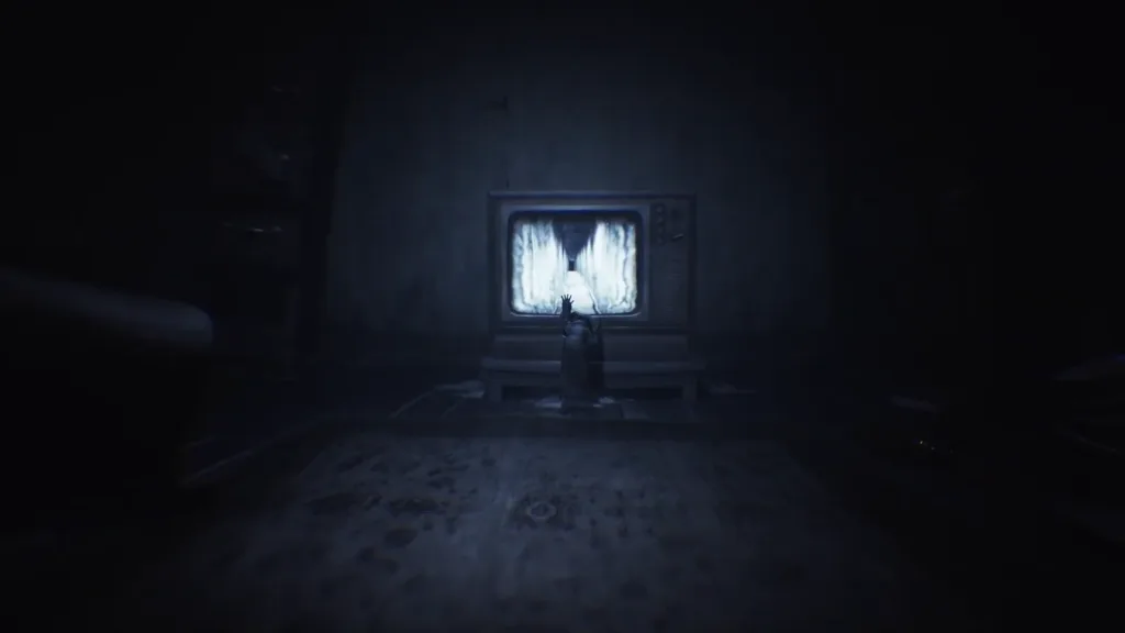 Criatura humanoide com a mão na tela de uma TV em sala escura em Little Nightmares II Enhanced Edition.