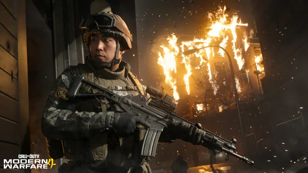 Soldado empunhando arma em local de noite com parte de um prédio pegando fogo ao fundo em Call of Duty Modern Warfare 4.