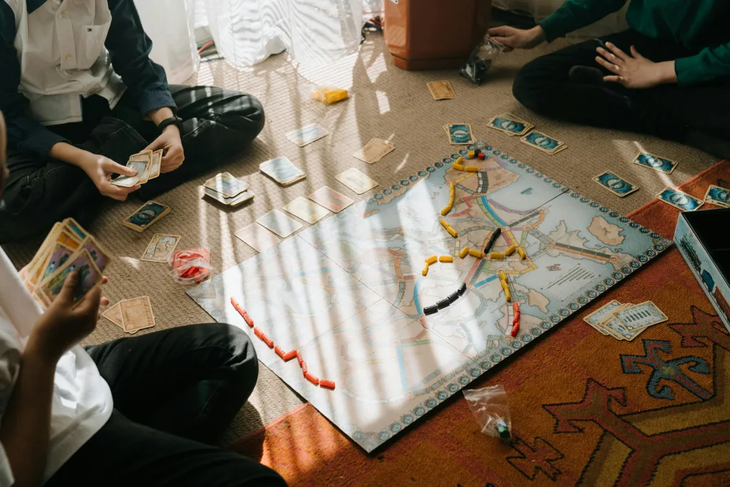 Pessoas jogando um jogo de tabuleiro moderno no tapete de uma casa.
