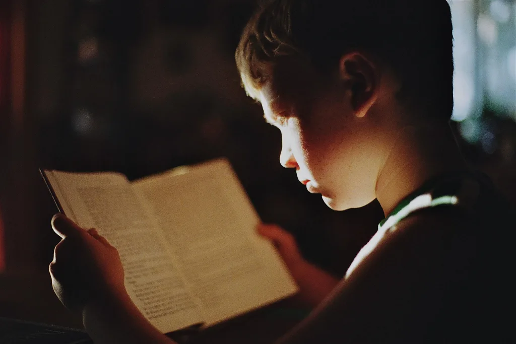 Garoto lendo um livro sobre luz indireta.
