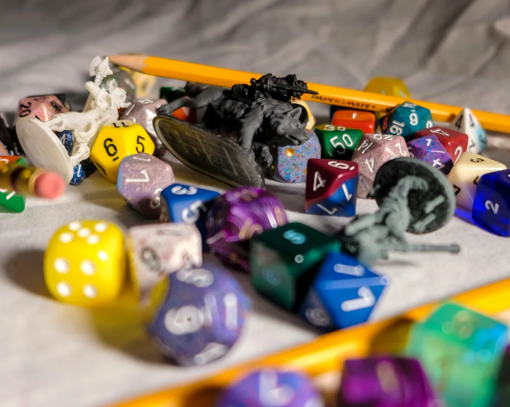 Dados, vários lápis e miniatura em cima de pano.