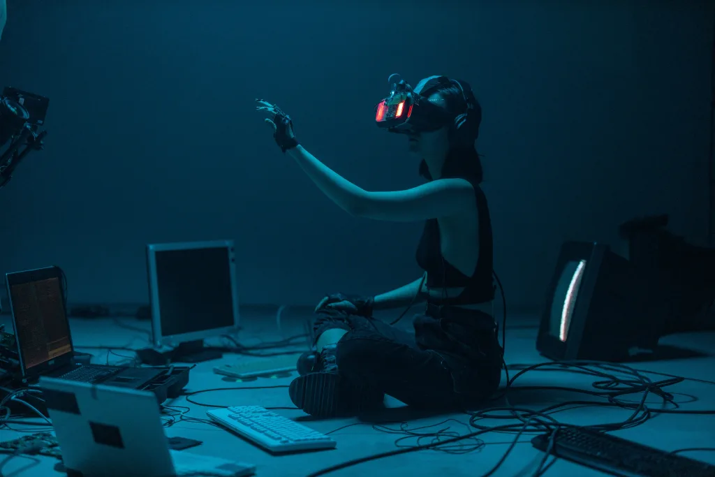 Pessoa sentada no chão mexendo com realidade virtual em meio a muitos computadores.
