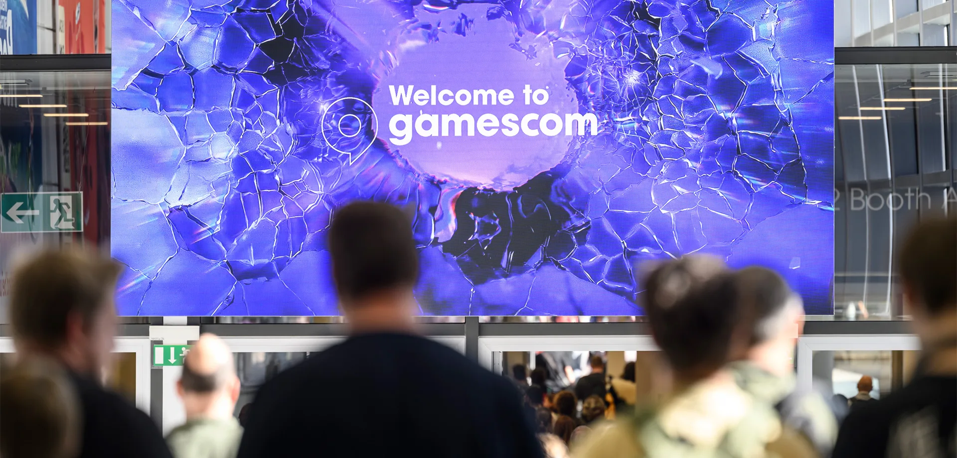 Foto da gamescom 2026 com pessoas à frente de um telão escrito "Welcome to gamescom".